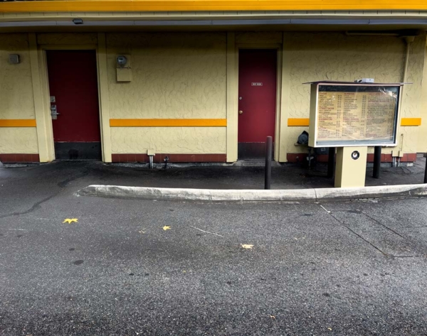 An old mexican drive up restaurant with faded menu sign next to bathroom door.