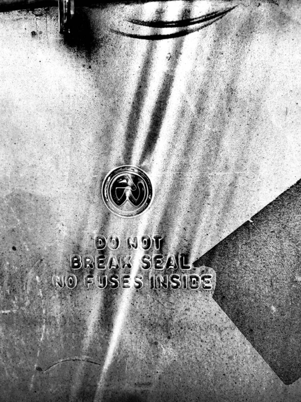 Contrasty black and white image of a device on a wall: do not break seal