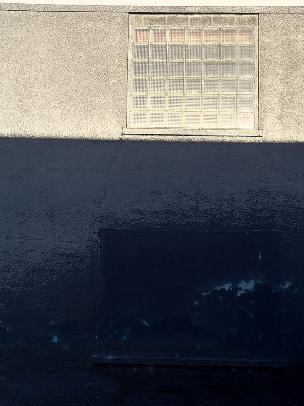 Blue wall below yellow textured wall with sunlit glass blocks