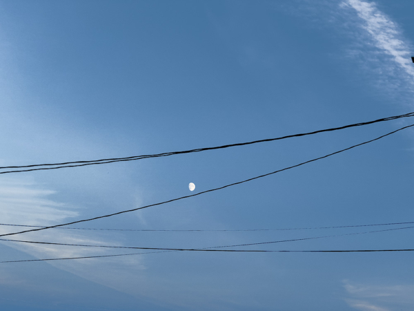 Black power lines against a blue white late mid-day streaked sky