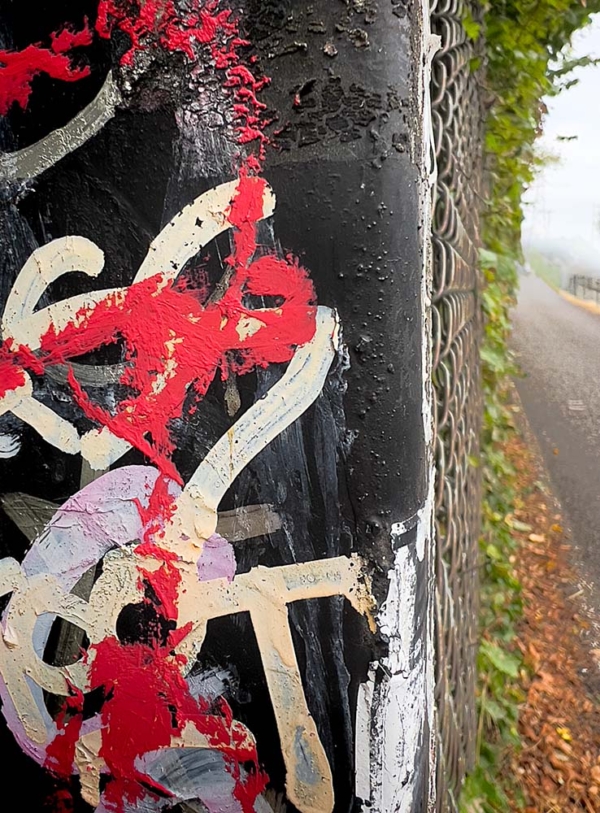 close up of graffiti on wall with bike trail on right portion of image